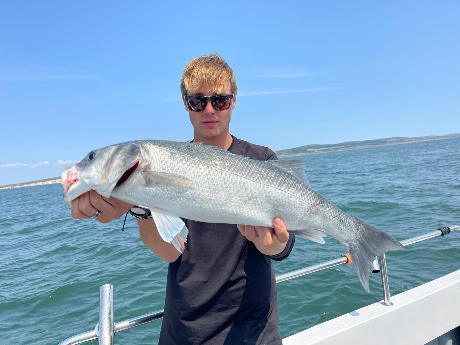Angler holding a large silver fish aboard Raptor