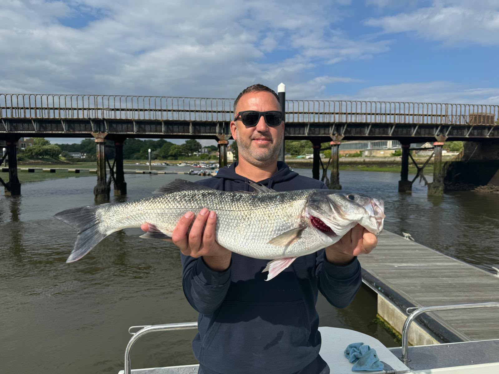 Angler holding a catch beside a pontoon