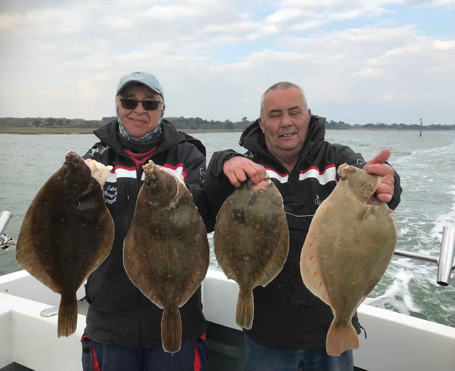 Two anglers displaying four flatfish aboard Raptor