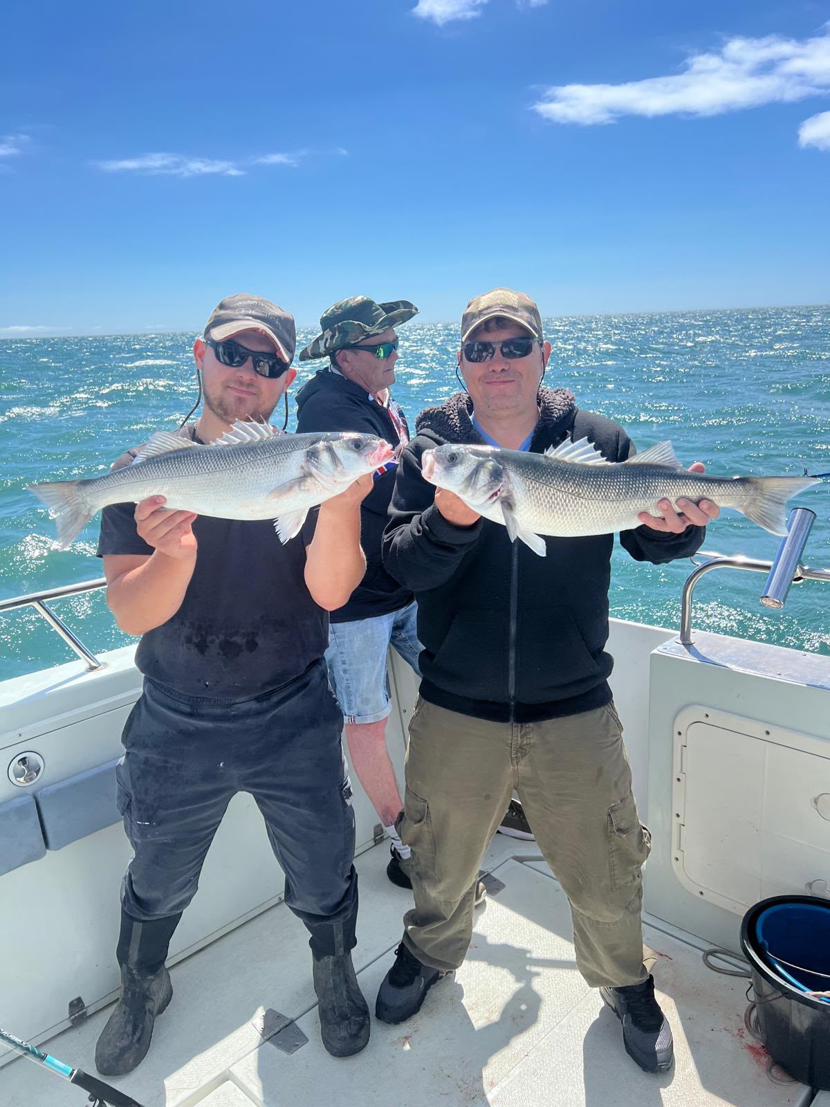 Two anglers displaying their catches on a sunny day