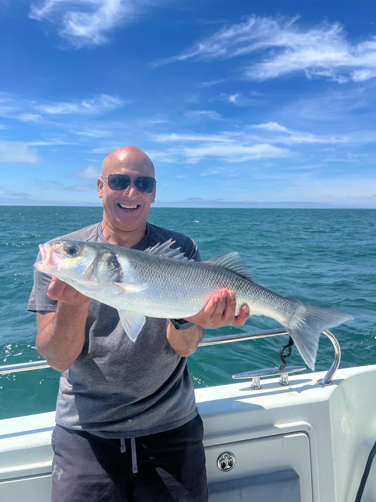 Smiling angler holding a catch at sea
