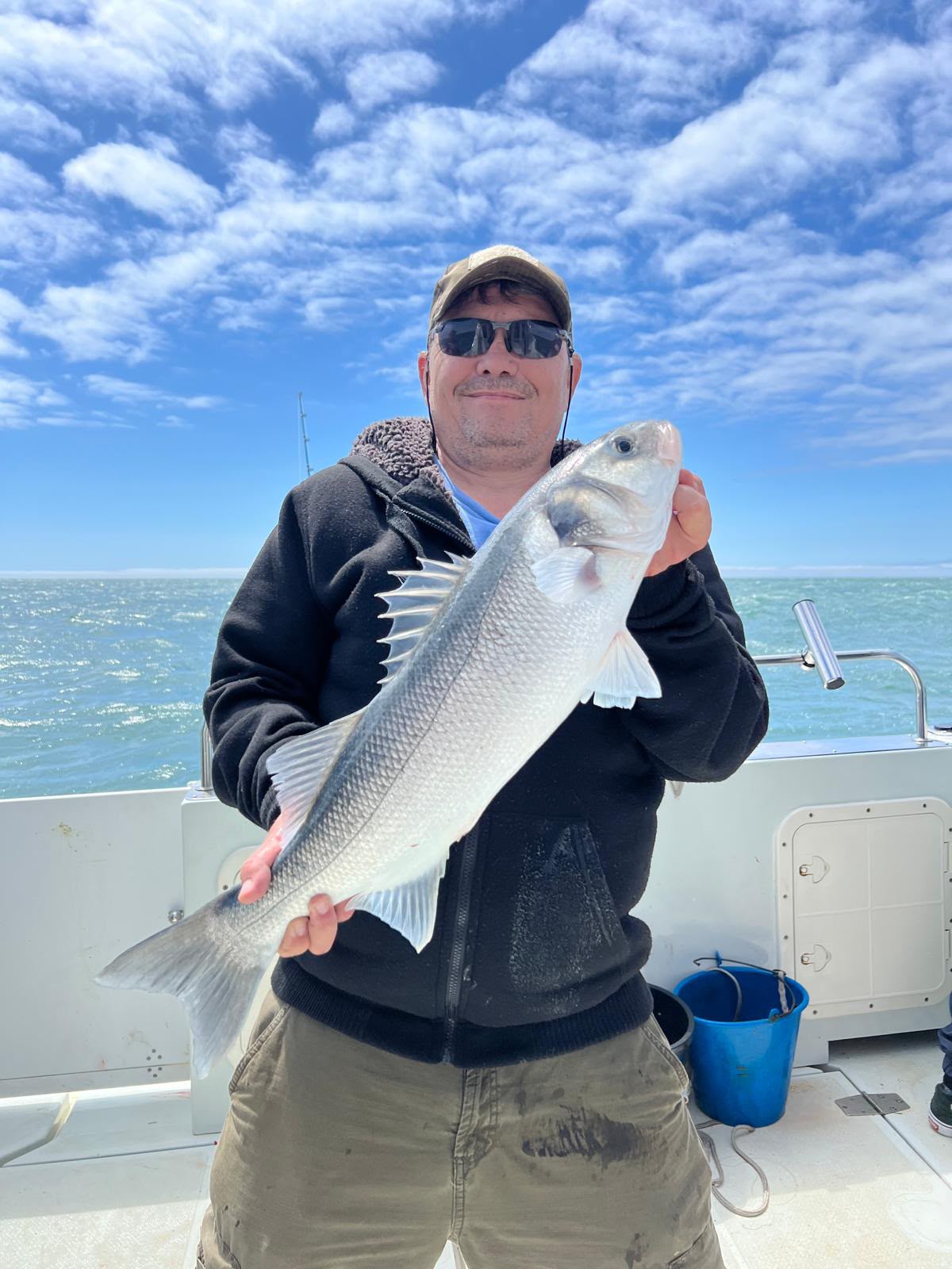 Angler displaying a catch beneath a bright blue sky