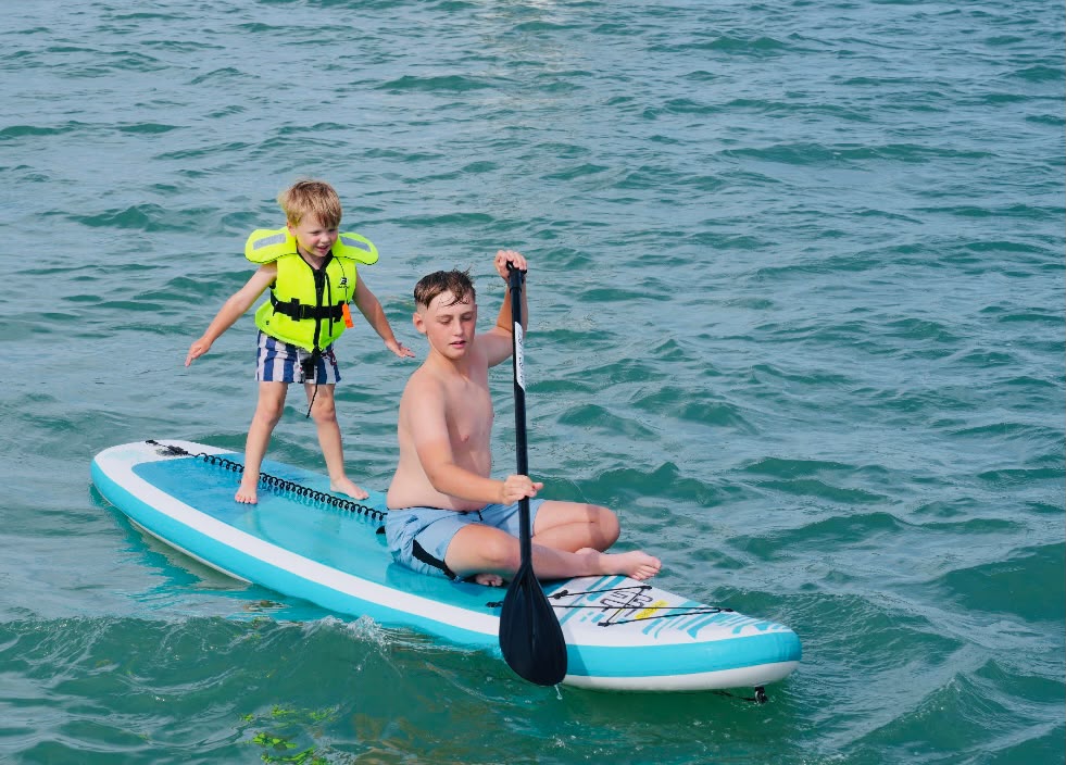 Two young guests sharing a paddleboard