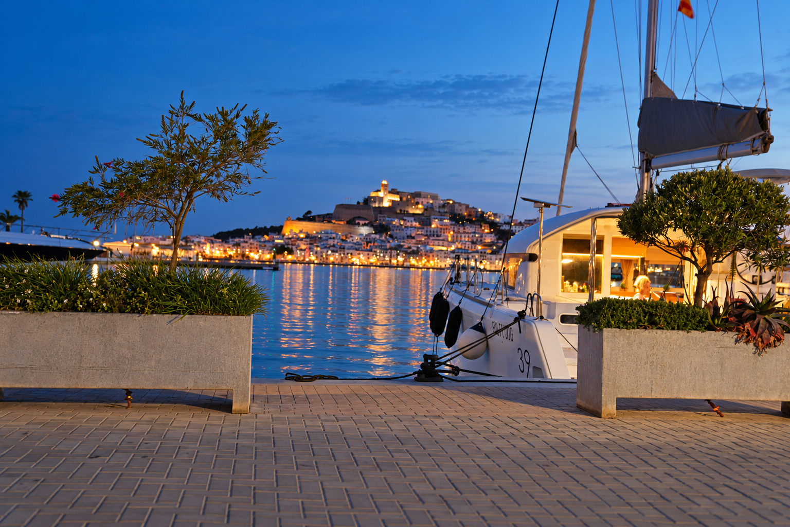 RaRa moored beside an illuminated Mediterranean harbour at blue hour